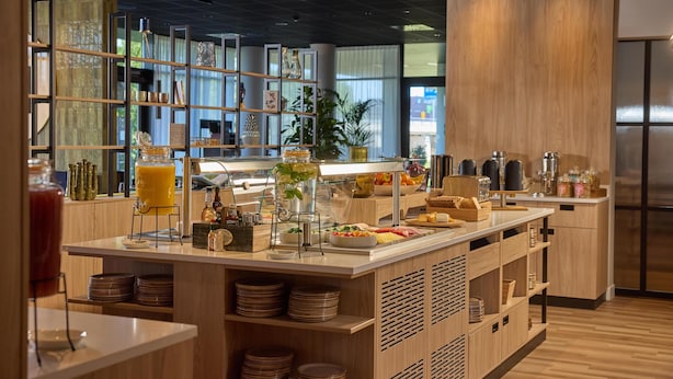 Eine moderne Frühstückstheke mit verschiedenen Speisen und Getränken, Holzböden mit Dekoration und Blick ins Freie.