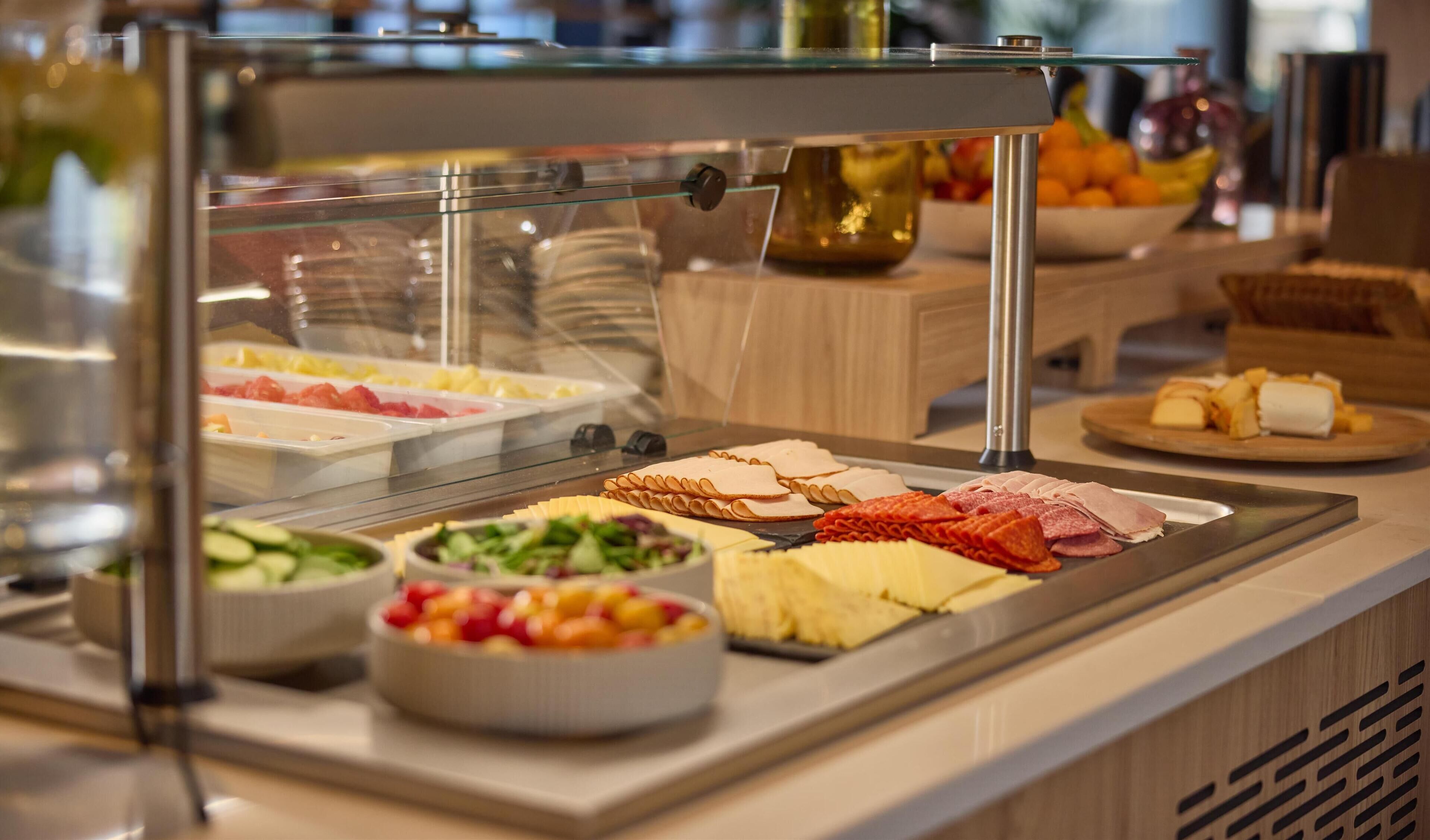 Een buffet met diverse gerechten, waaronder vleeswaren, kazen en salades.