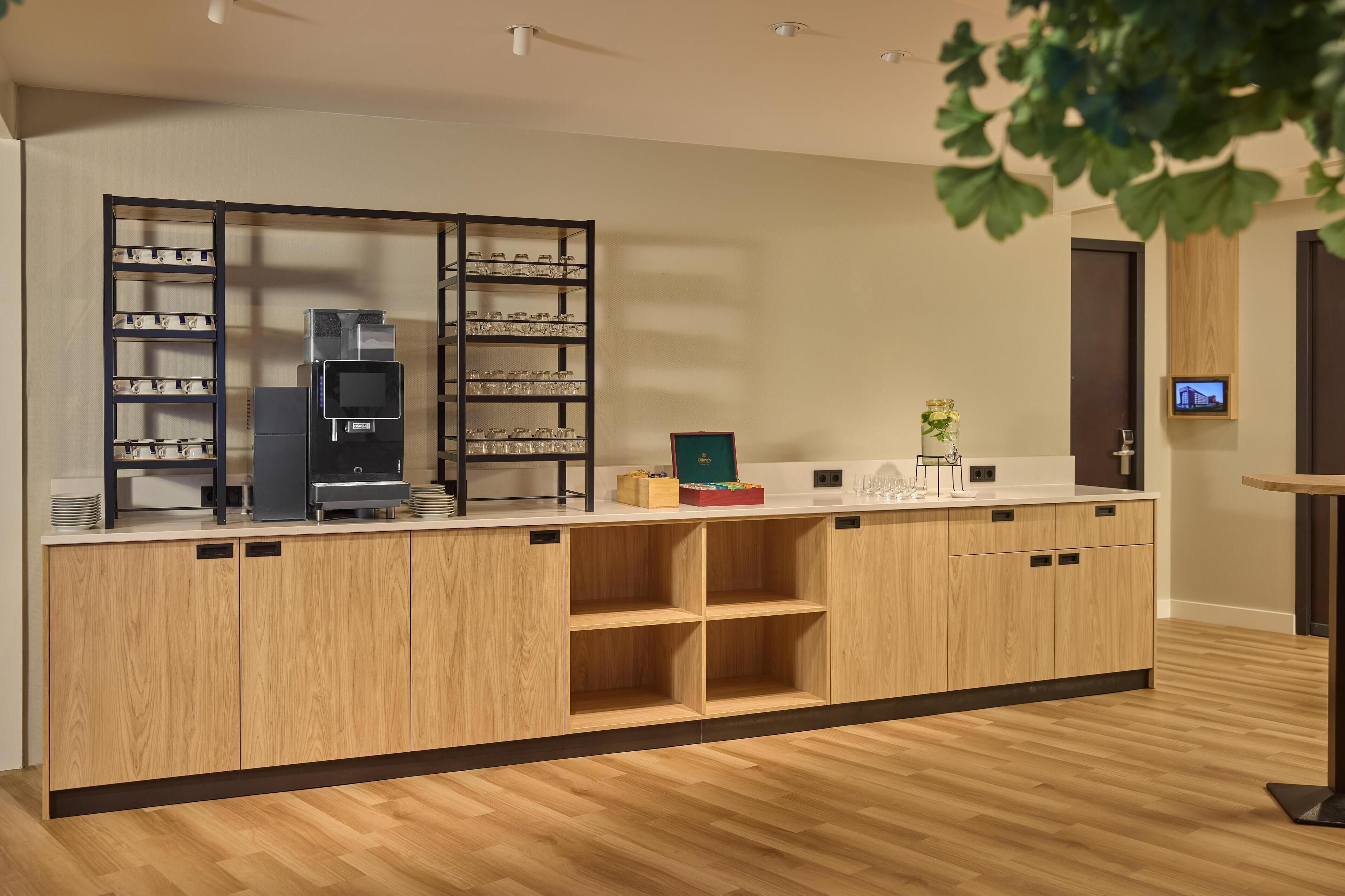 A modern kitchen with wooden cabinets, a coffee machine, and a glass display case.