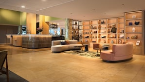 Eine moderne Lobby mit Empfangstresen, Sitzgelegenheiten und einer Wand mit Dekorationselementen.