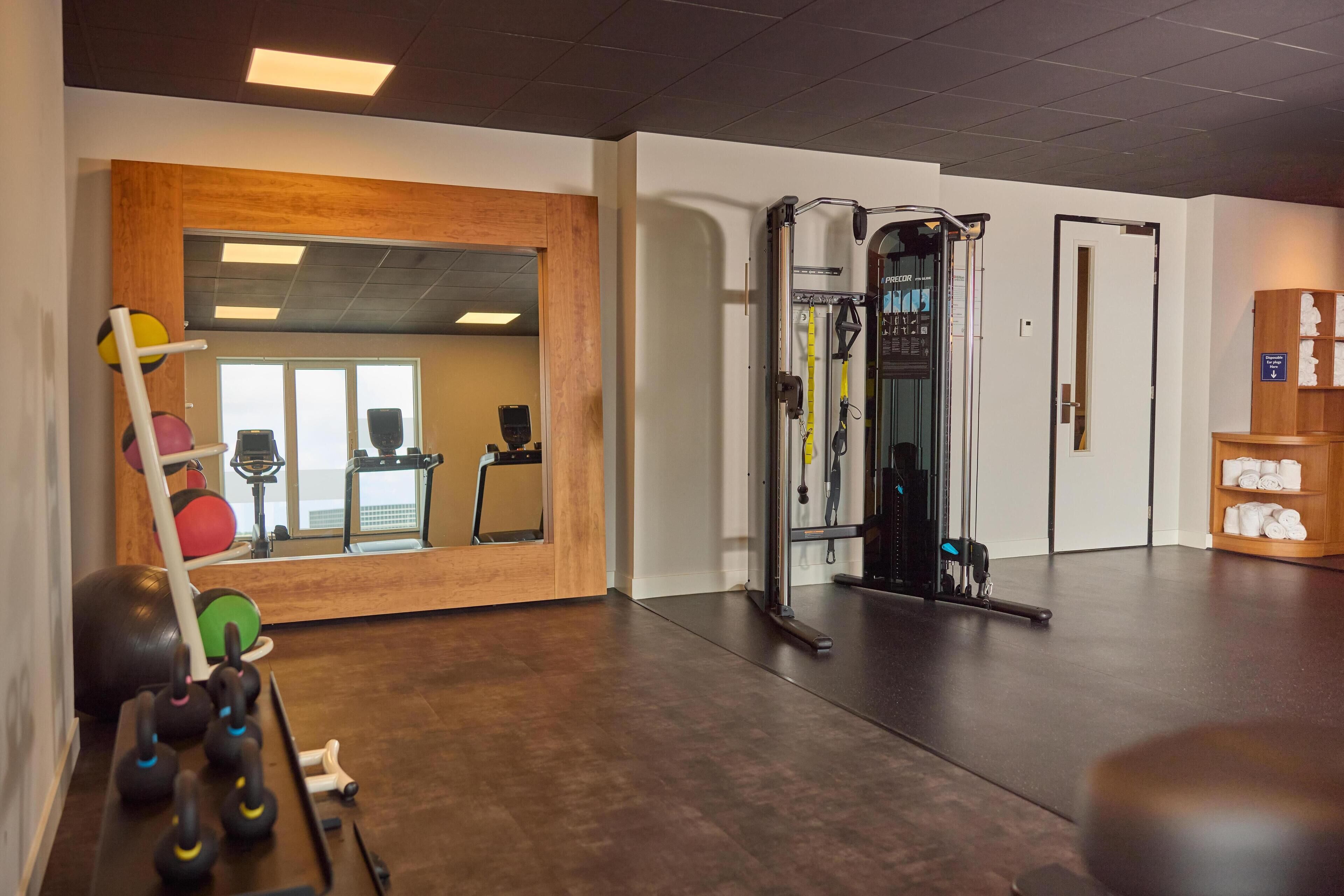 A gym with exercise equipment, a mirror, and a wooden wall.