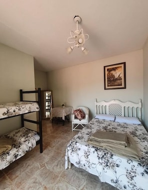 A bedroom with bunk beds, a single bed, a table with a chair, and a ceiling fan. - Nevada Ubatuba Hotel (Ubatuba)