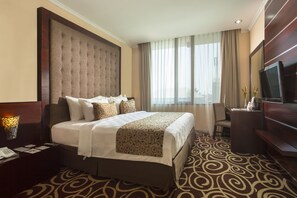 Relax in comfort with a large tufted headboard bed, flat-screen TV, and desk with chair.