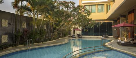 Alberca al aire libre, sombrillas en la alberca y camastros