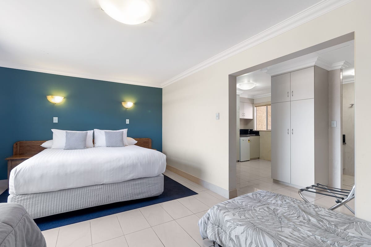 A bedroom with a double bed, a small bedside table, a chair, and a wardrobe.