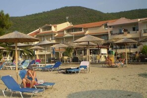 A beachside hotel with multiple balconies, sun loungers, and thatched umbrellas. - Rachoni Resort (Thasos)