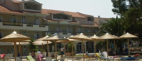 Hotel à beira-mar com várias varandas, guarda-sóis e espreguiçadeiras.