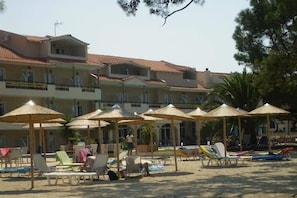 A beachside hotel with multiple balconies, sun umbrellas, and lounge chairs. - Rachoni Resort (Thasos)