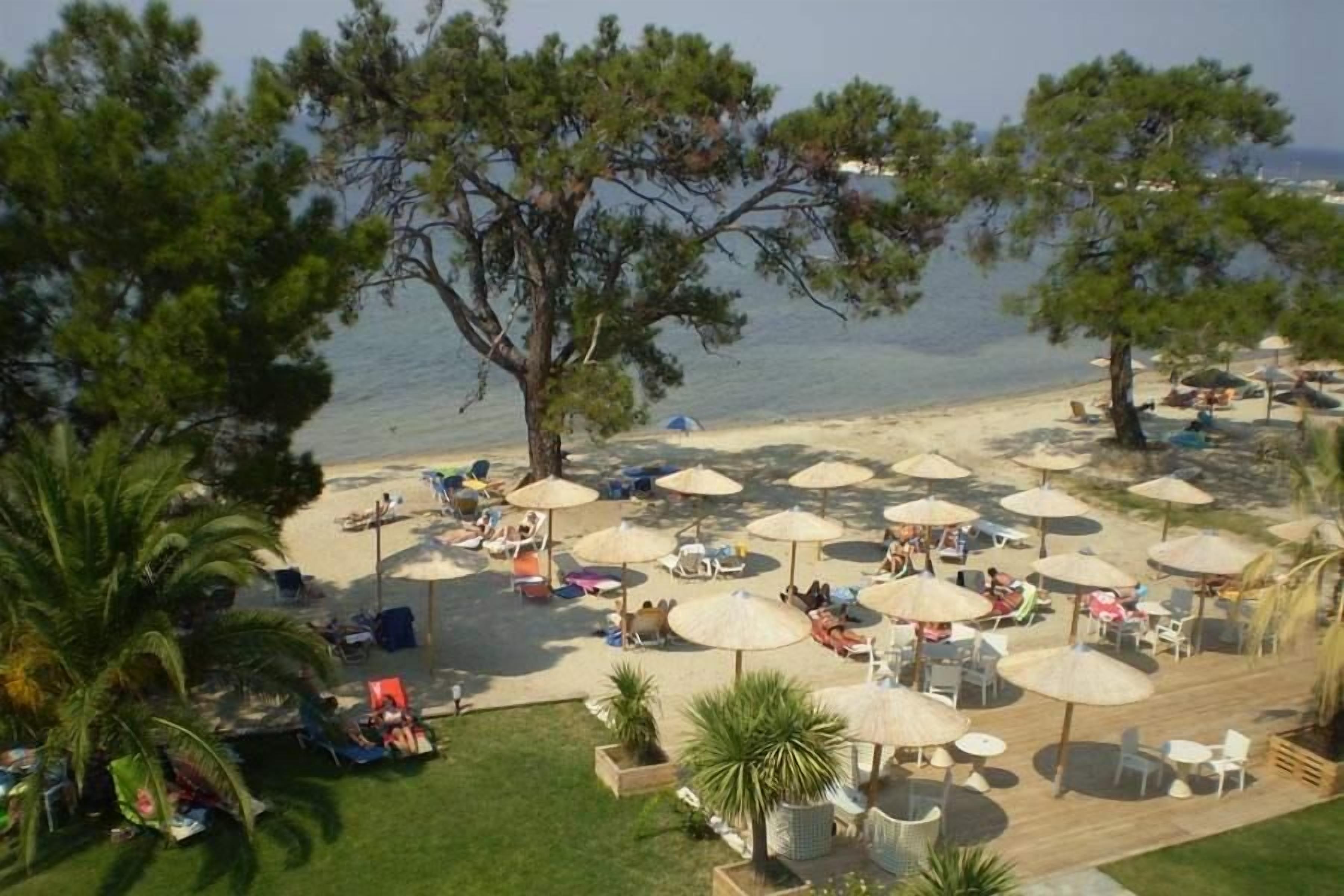 A beachside resort with outdoor seating areas, umbrellas, and a view of the sea.