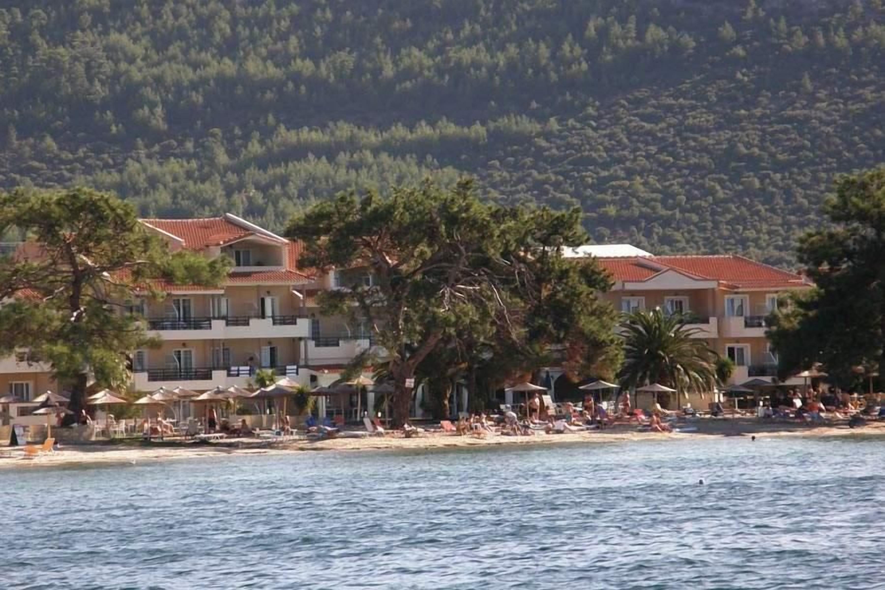 Un hotel frente al mar con varios balcones, asientos en la playa y vistas al océano.