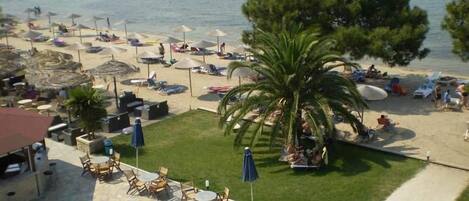 A beachside hotel with a pool, lounge chairs, umbrellas, and a view of the sea.