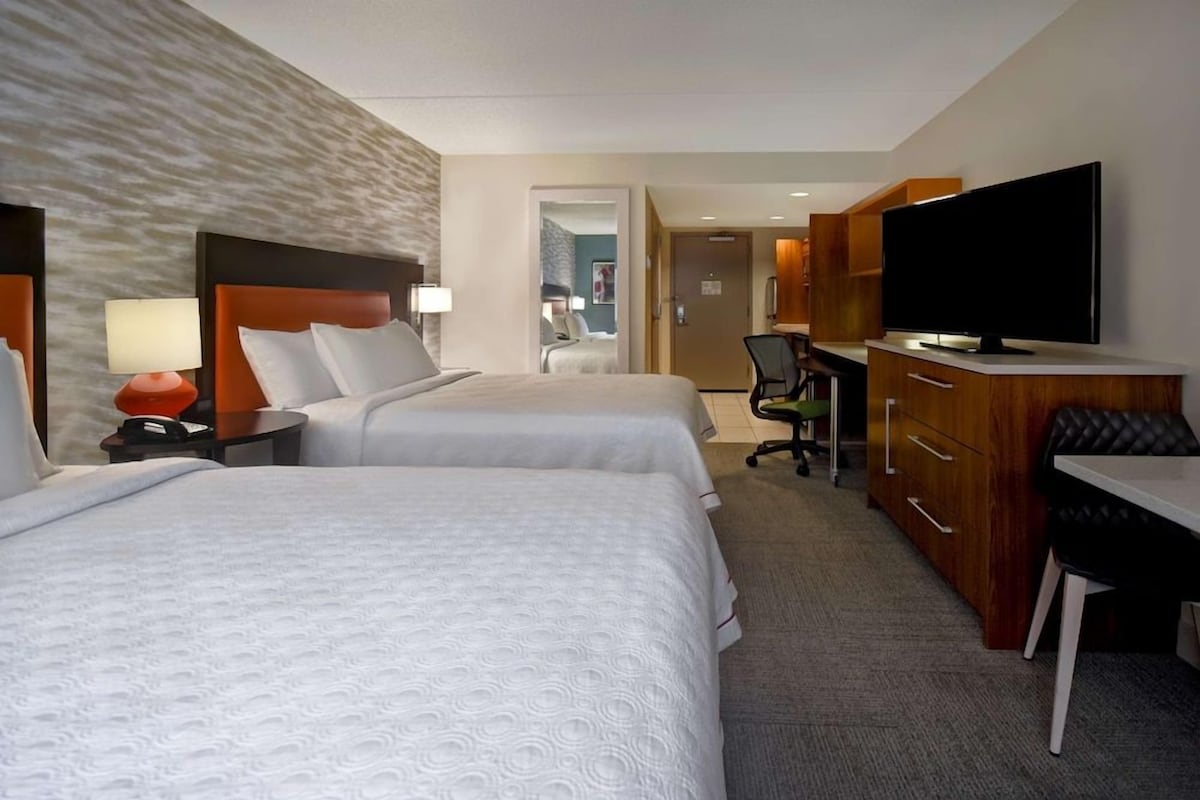 Une chambre d’hôtel avec deux lits, un bureau, une télévision et une armoire.