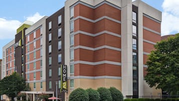 A multi-story hotel with a modern design, featuring a prominent 'HOME2' sign, a brick facade, and a flat roof.