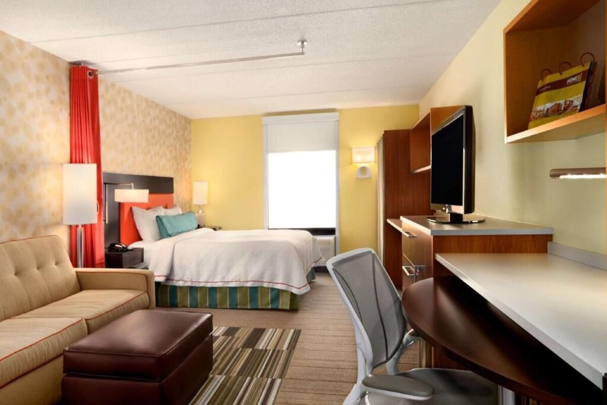 Une chambre d’hôtel équipée d’un lit, d’un bureau, d’une chaise, d’une télévision et d’un canapé.