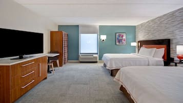 A hotel room with a flat-screen TV, a desk, two beds, a wardrobe, and a window with a view.