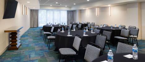 A conference room with multiple tables and chairs, equipped with water bottles and nameplates.