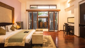 A hotel room with a bed, two bedside tables, a desk, and a chair. - Cattleya Suite by Marbella (Keroboken Kelod)