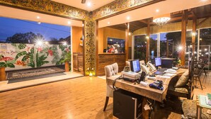 A spacious room with a wooden floor, a desk with computers, and a large mirror reflecting the room. - Cattleya Suite by Marbella (Keroboken Kelod)