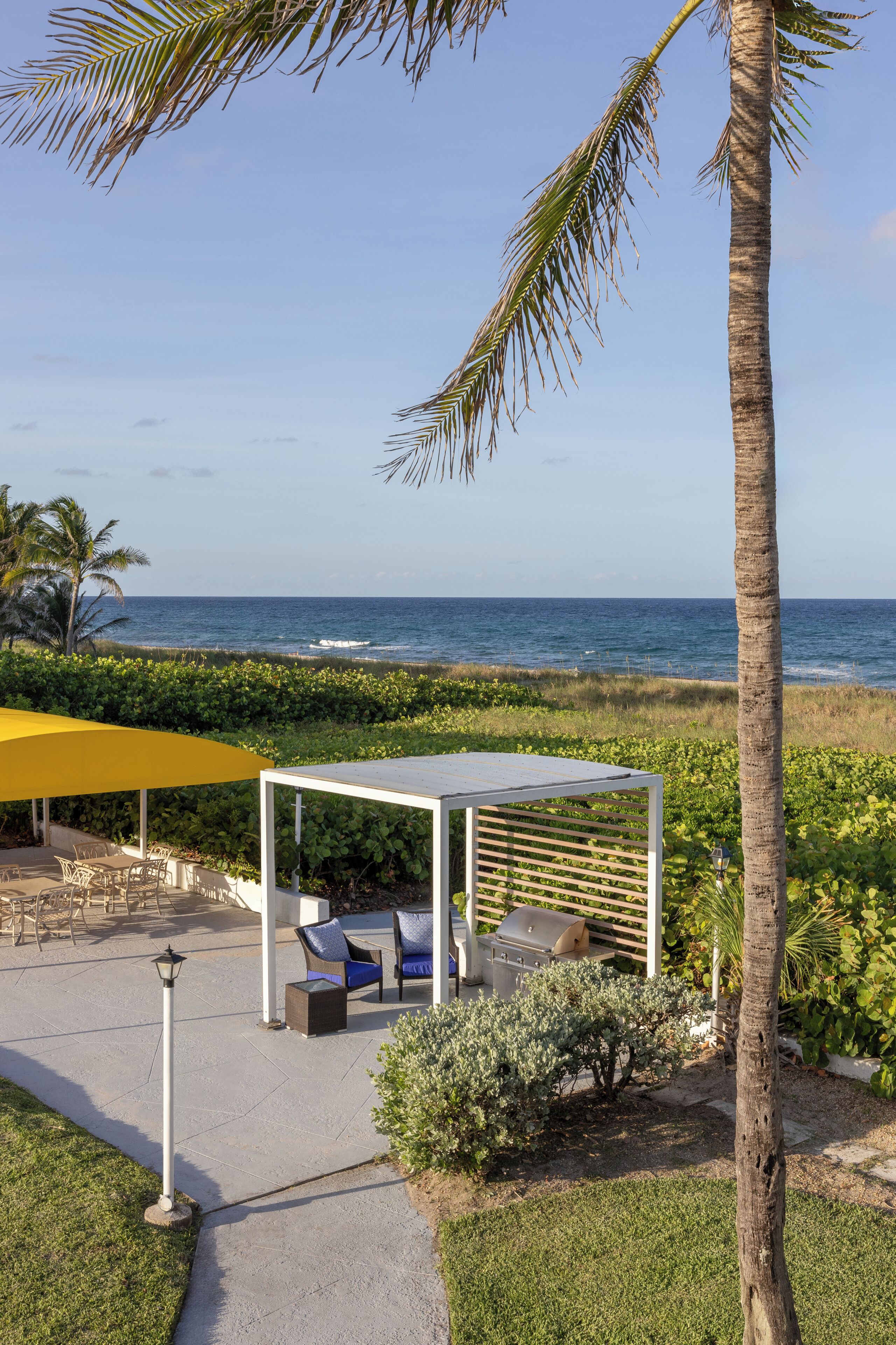 A patio area with outdoor furniture, a grill, and a view of the ocean.