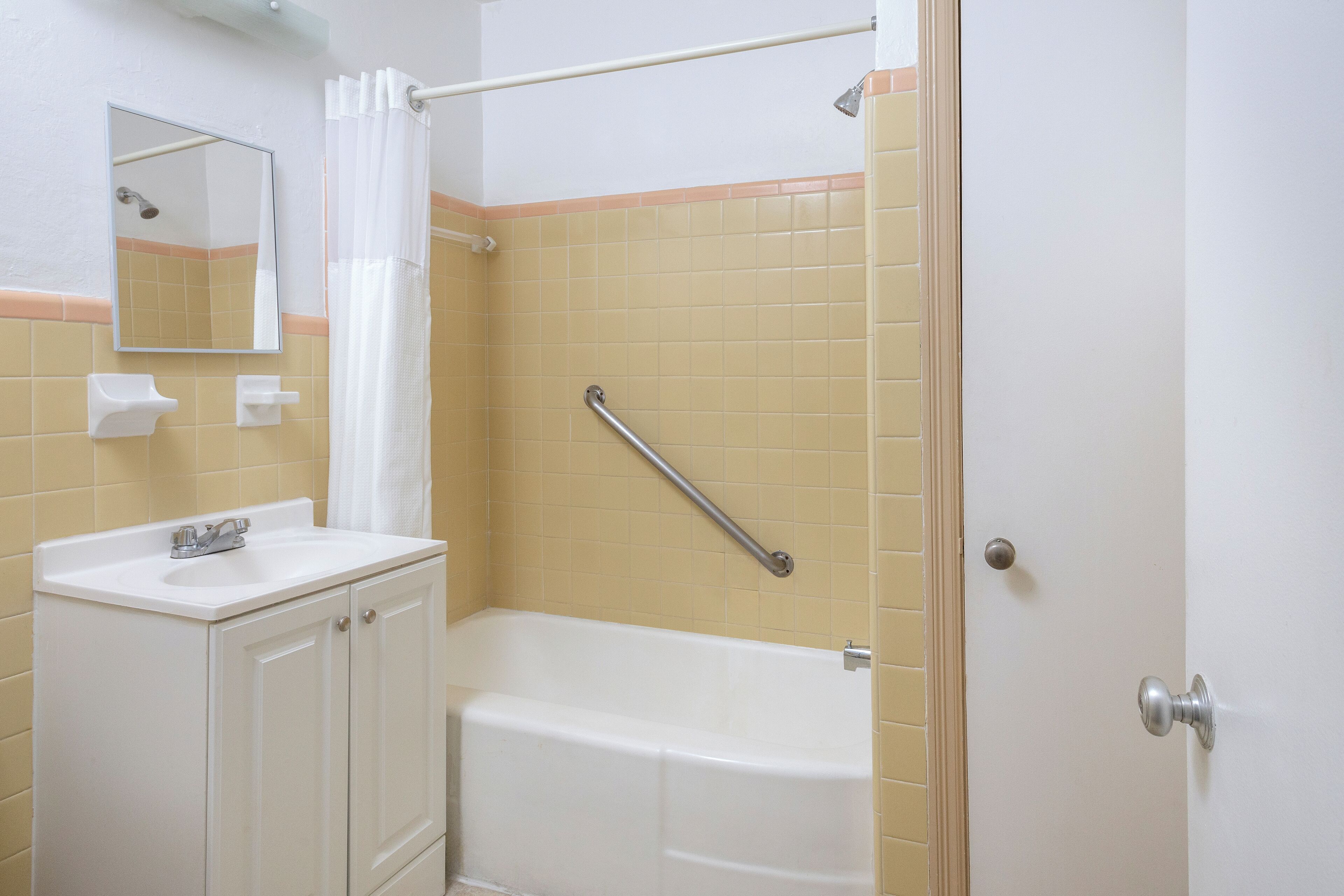 Une salle de bain avec un lavabo blanc, un miroir et une baignoire.