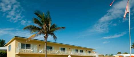 A two-story motel with a balcony on the second floor, a flagpole with an American flag, and a well-maintained lawn.