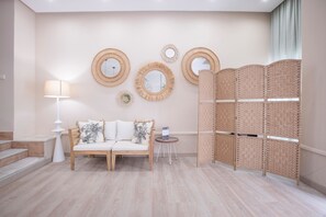 Una habitación con un sofá, una mesita, una lámpara y un muro decorativo con espejos y un panel tejido.