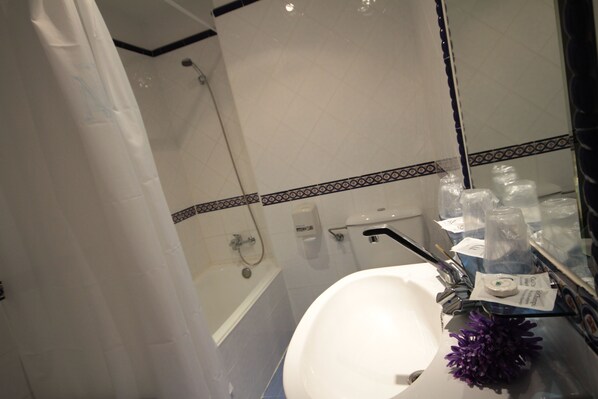 A bathroom with a white sink, a mirror, and a shower area.