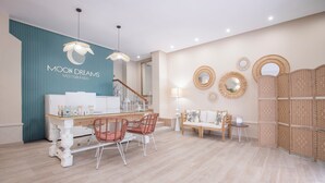 Un moderno vestíbulo de hotel con mostrador de recepción, zona de estar y elementos decorativos en la pared.