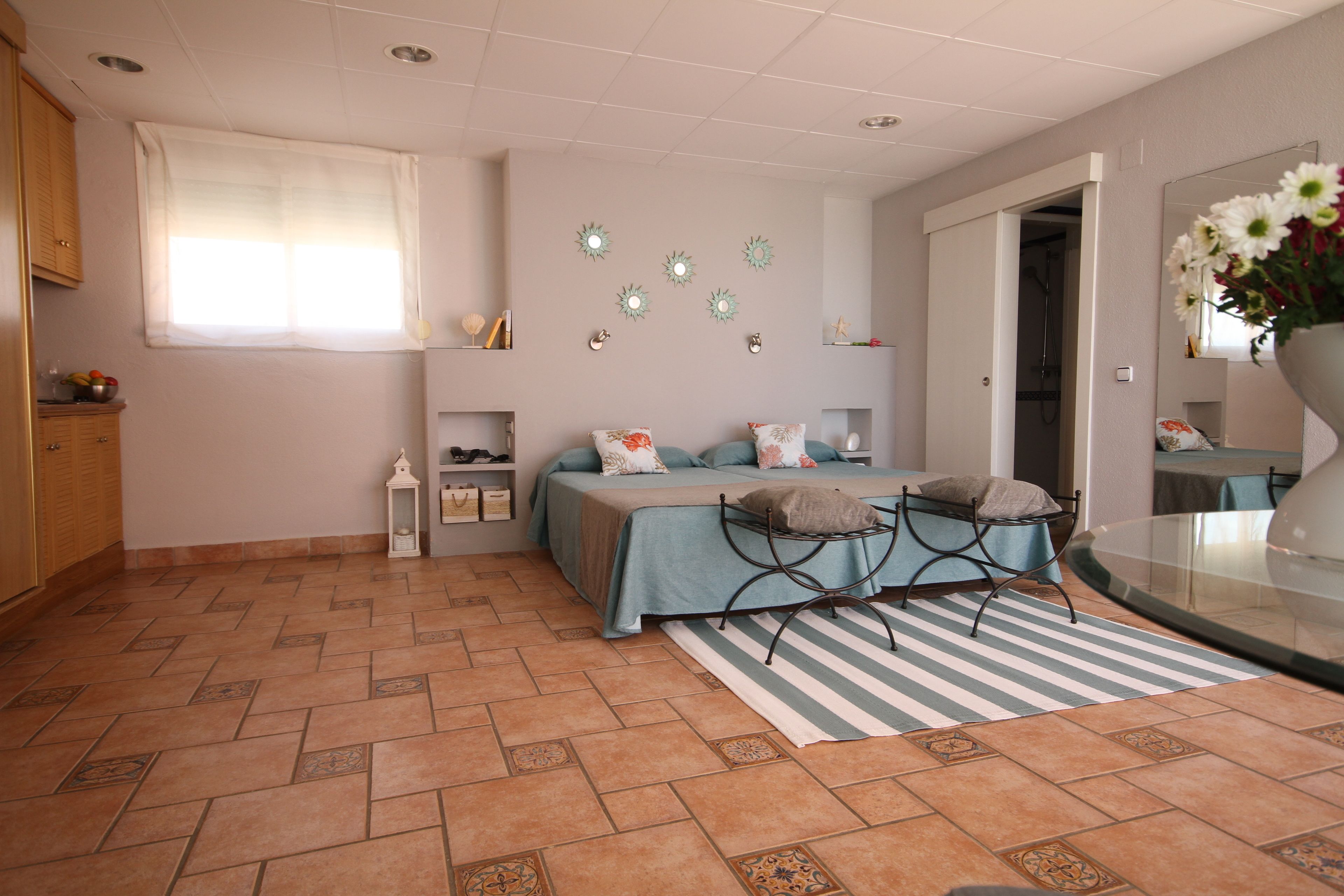 Een slaapkamer met een bed, een stoel, een raam en een spiegel.