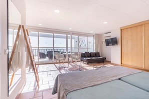 Une chambre avec un lit, une télévision, un balcon avec vue et un tableau au mur.
