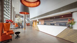 Eine moderne Hotelhalle mit Empfangsschalter, Sitzgelegenheiten und einer Treppe.