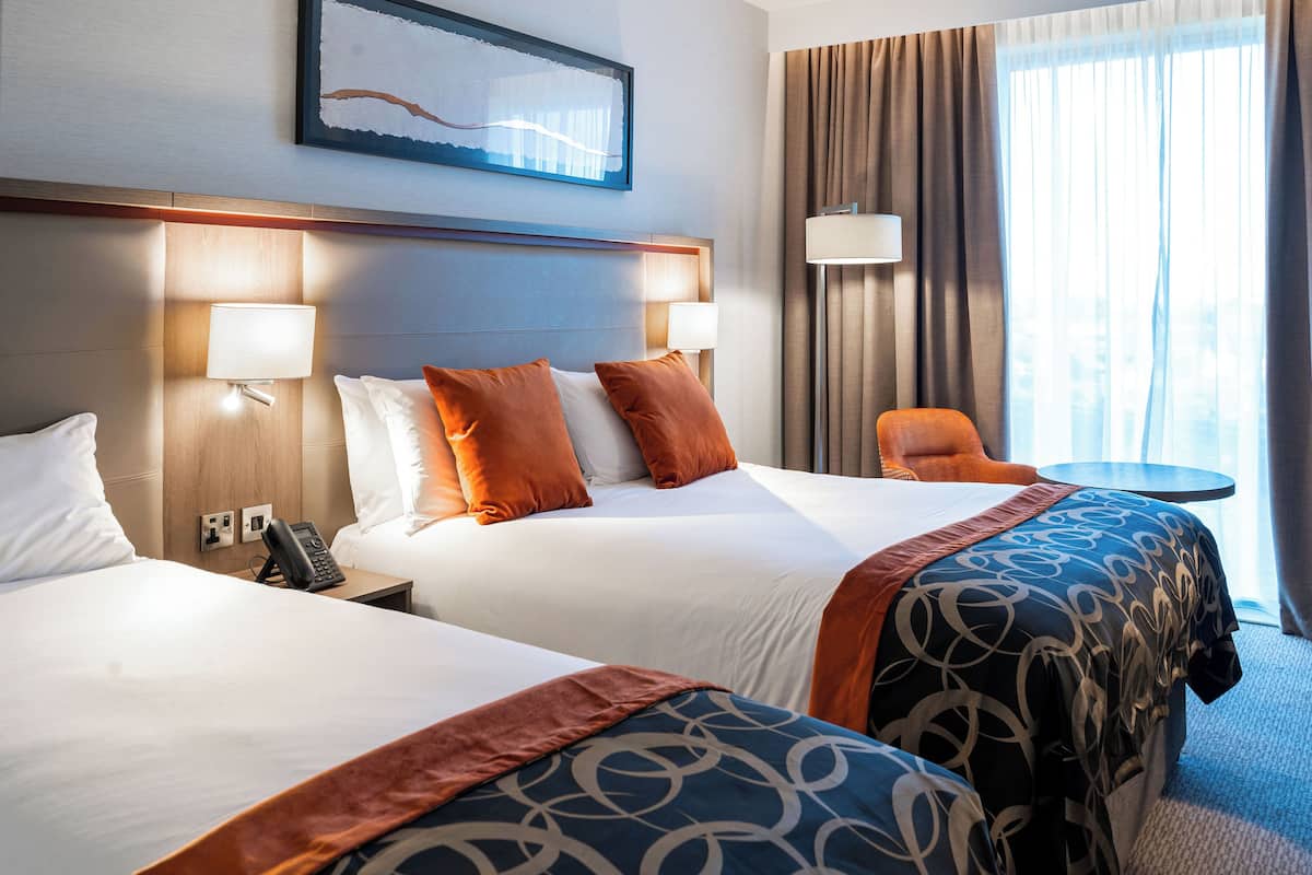 Ein Hotelzimmer mit zwei Betten, einem kleinen Tisch und einem Stuhl.