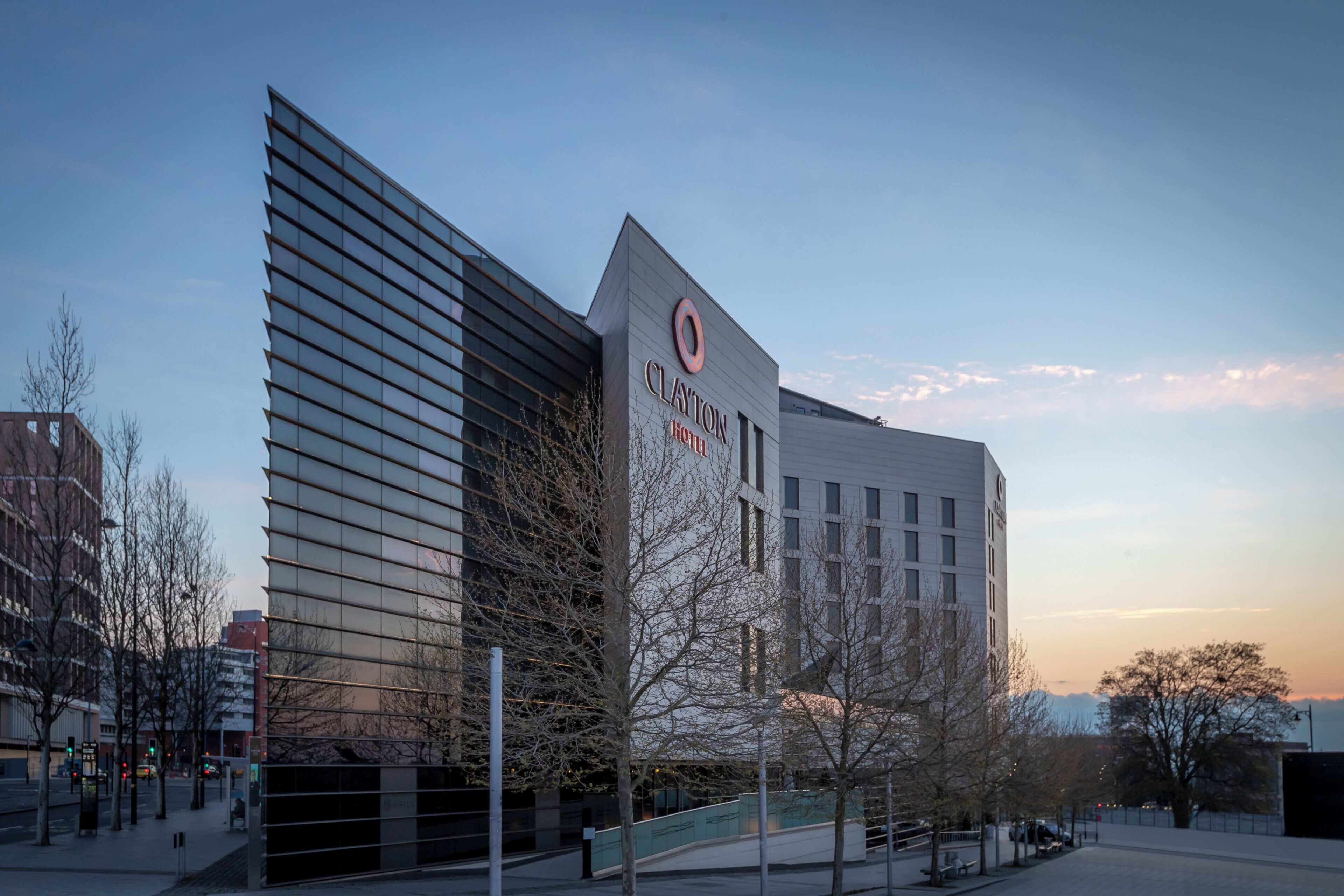 A modern hotel building with a prominent logo, large windows, and a flat roof.