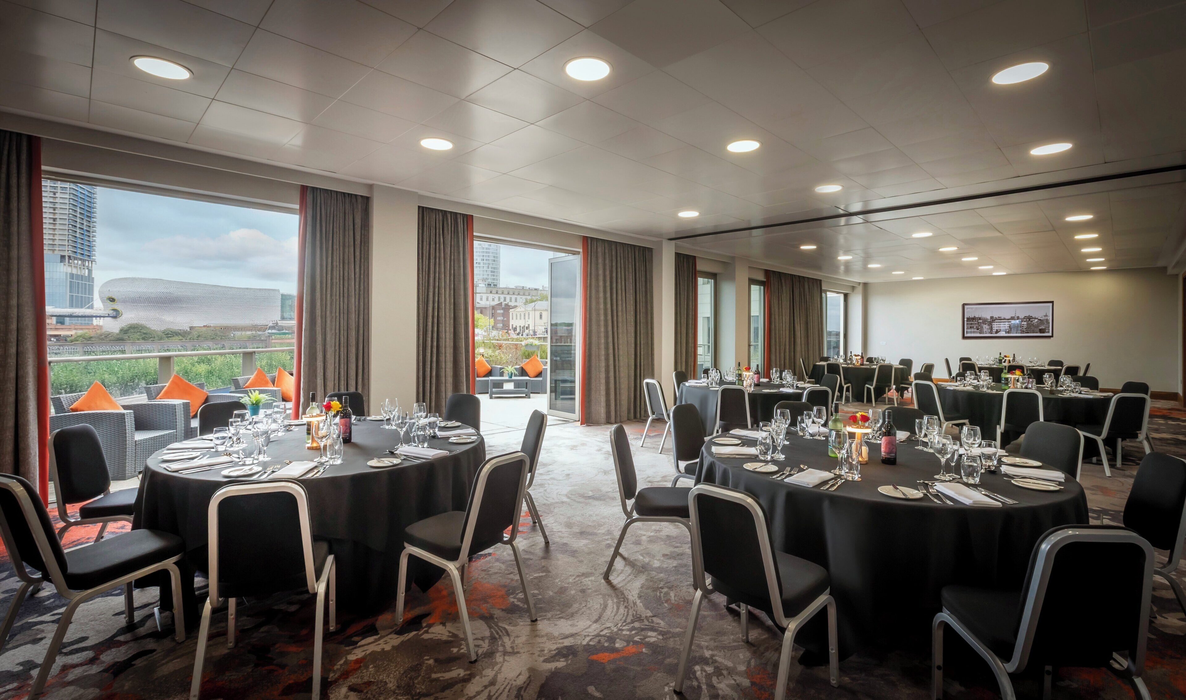 A conference room with round tables, chairs, and a city view.