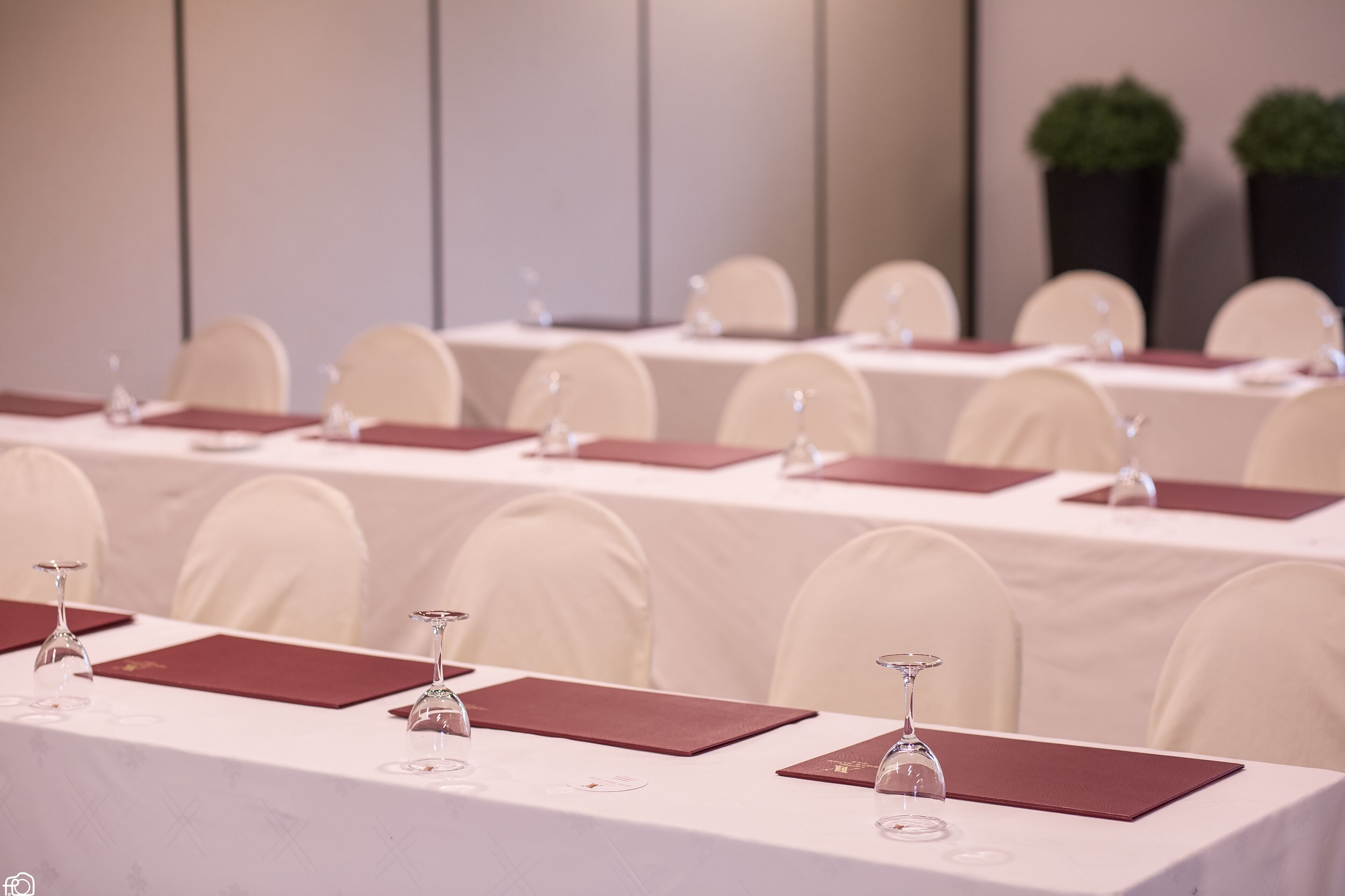 Un salón de conferencias con varias mesas, cada una con una copa de vino y una placa de identificación.