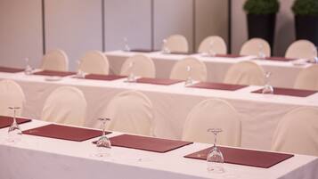 Un salón de conferencias con varias mesas, cada una con una copa de vino y una placa de identificación.