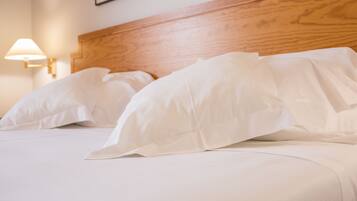 A neatly made bed with white linens and a wooden headboard.