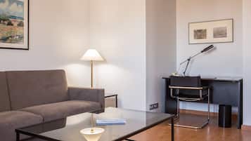 Un salon moderne comprenant un canapé, une table basse en verre, un bureau avec une chaise et une lampe.