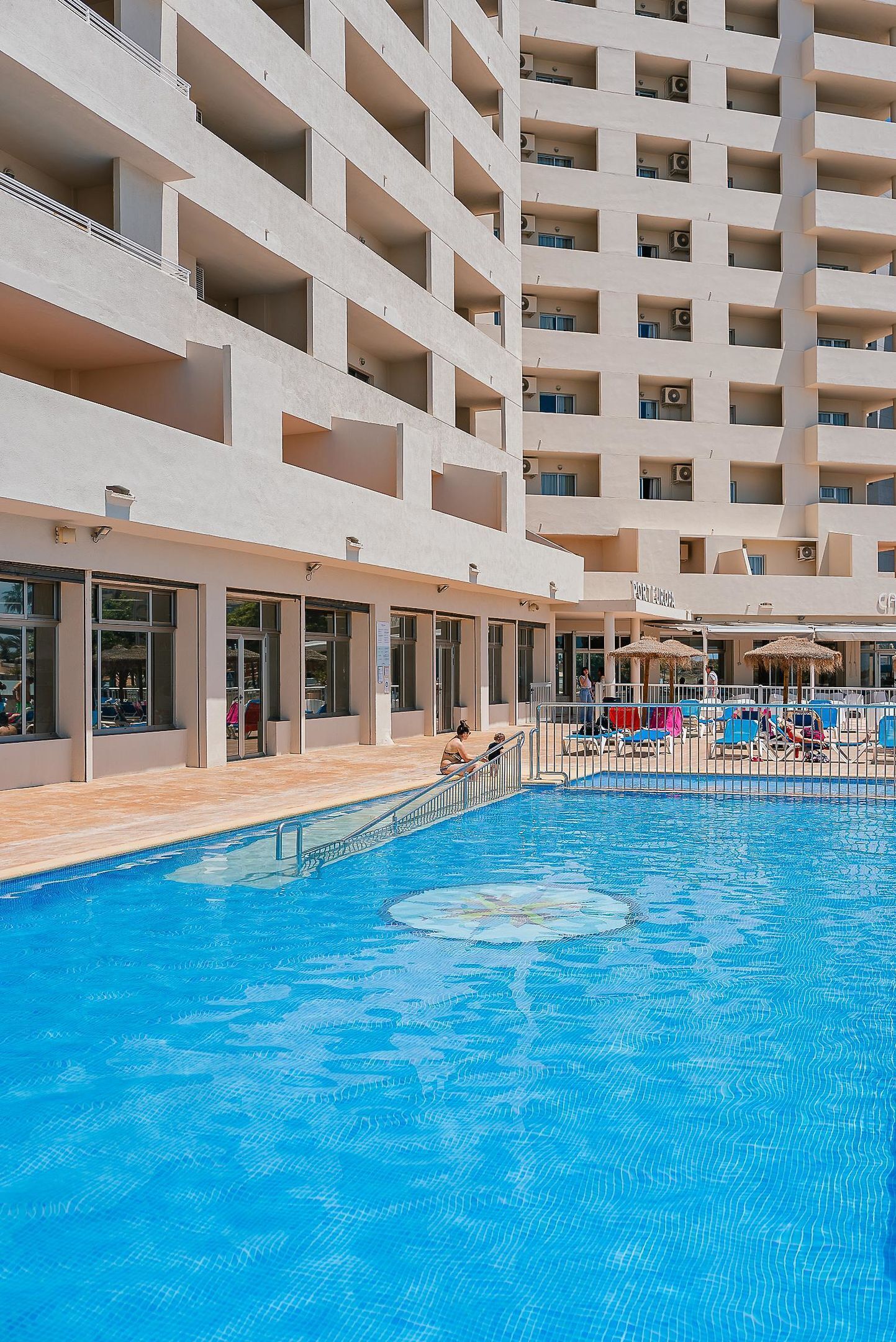 Een hotel met een zwembad, meerdere balkons en buiten zitgedeeltes.