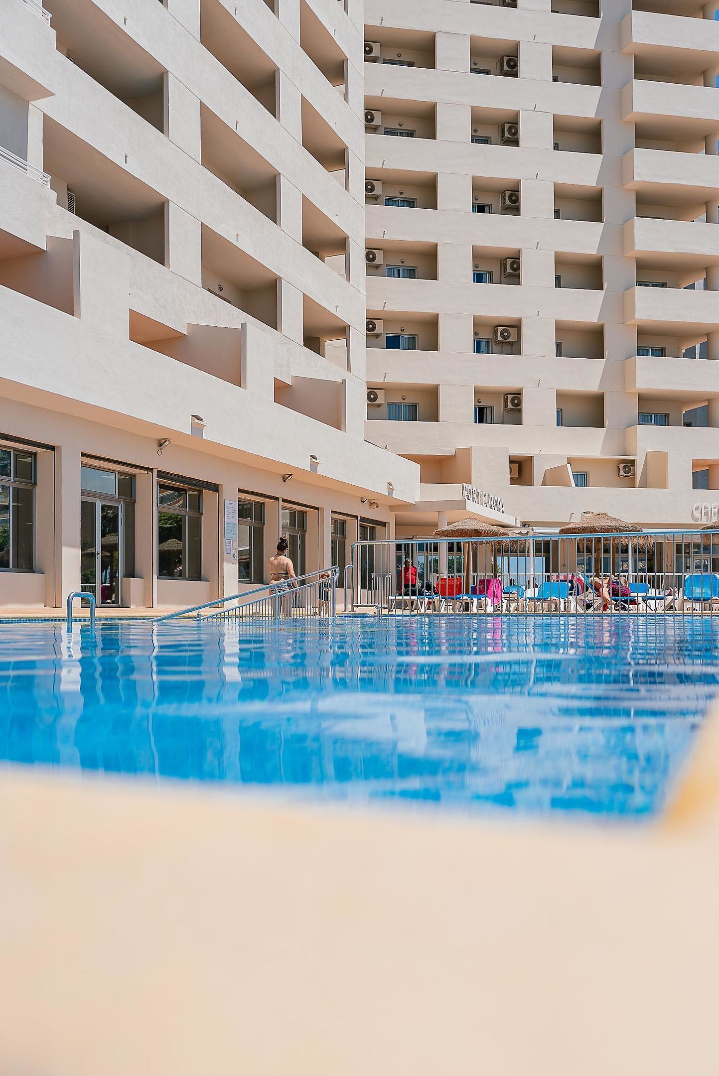 A hotel with multiple balconies and a swimming pool area.