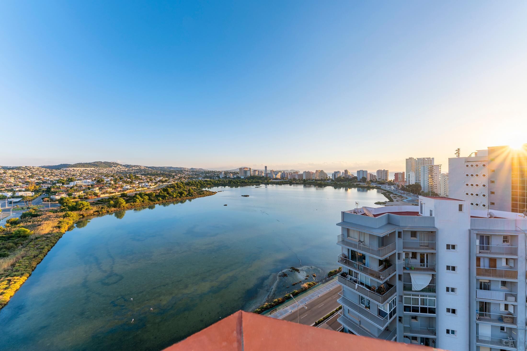 Un edifici alt amb nombroses balconades que donen vista a un riu i al paisatge urbà.