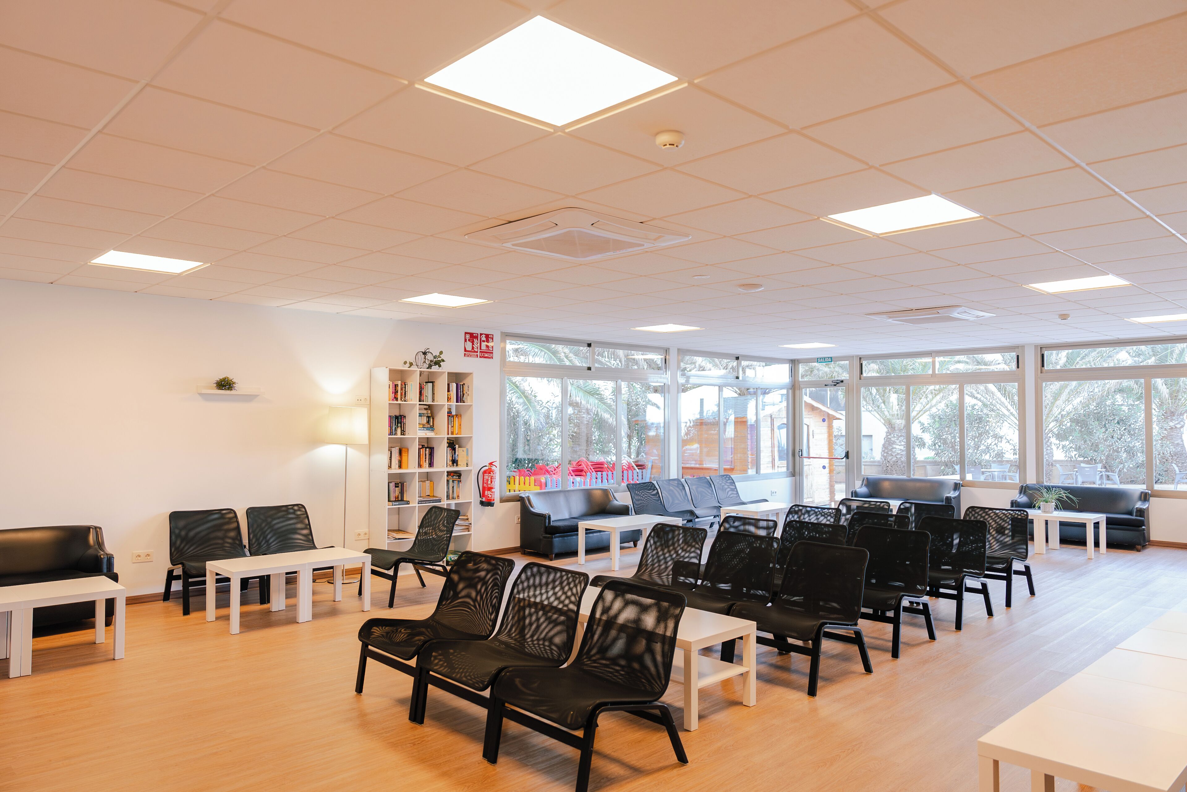 A spacious room with a long table, several chairs, a sofa, and a bookshelf.