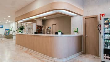A reception area with a curved wooden counter, a vending machine, and a door.