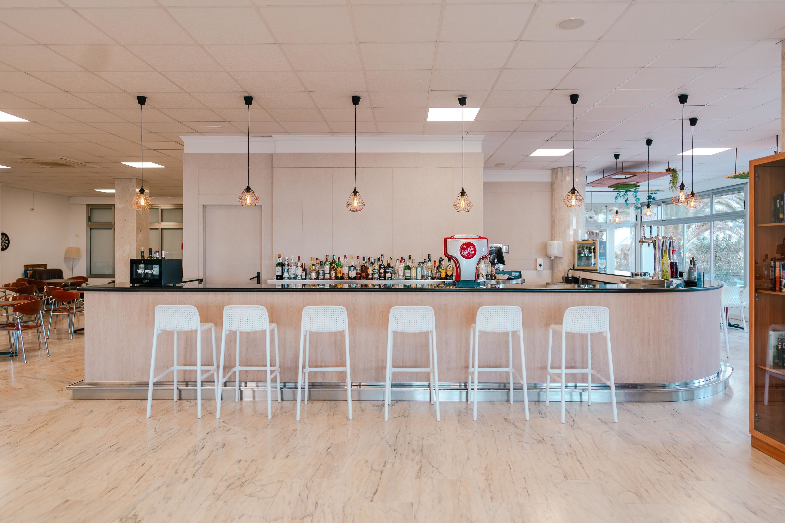 A bar area with a counter, bar stools, and a variety of bottles.