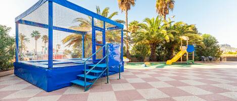 A playground with a blue climbing structure and a yellow slide.