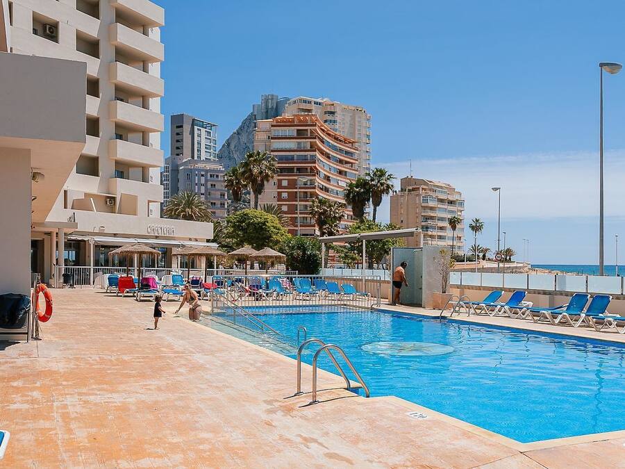 Zona de piscina de hotel con sillas de descanso y puesto de socorristas.