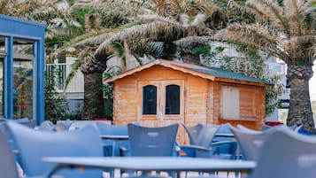 A beachfront setting with a small wooden structure, possibly a cabana, surrounded by palm trees.