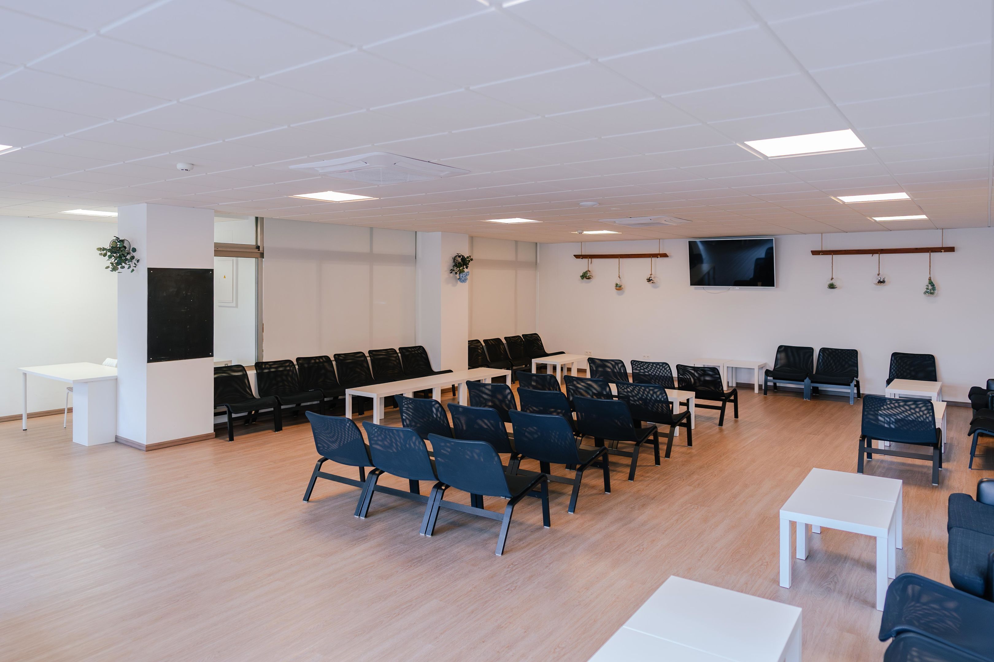 Ett konferensrum med rader av stolar, ett vitt bord och en platt-TV på väggen.