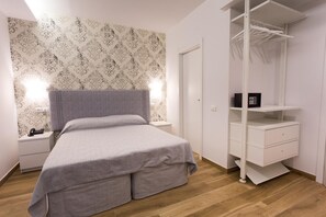 A bedroom with a bed, nightstands, a wardrobe, and a patterned wallpaper. - Maria Rosaria Bed & Breakfast (Ladispoli)