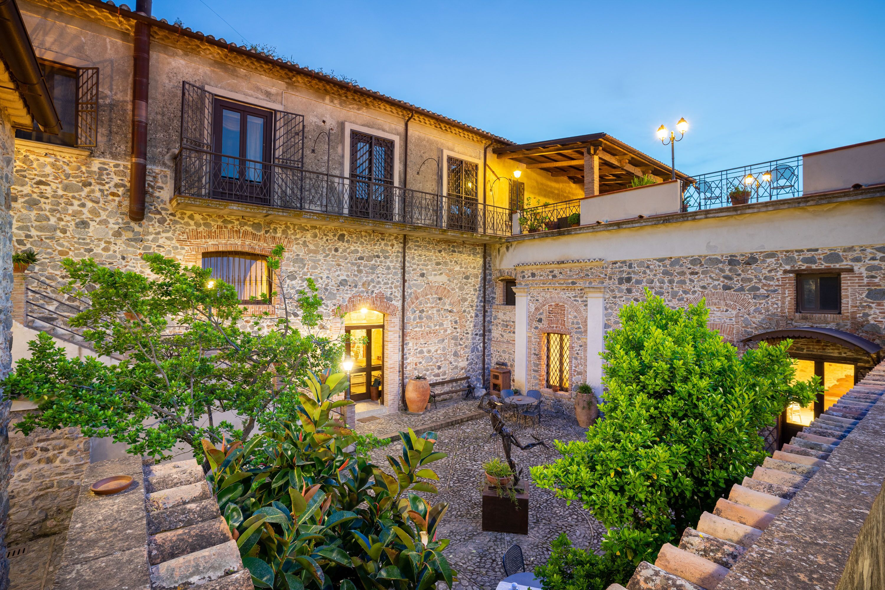A courtyard with stone buildings, outdoor seating, and potted plants.